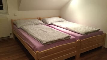 A single wooden bed with a wooden headboard and footboard, a purple mattress, and two pillows.