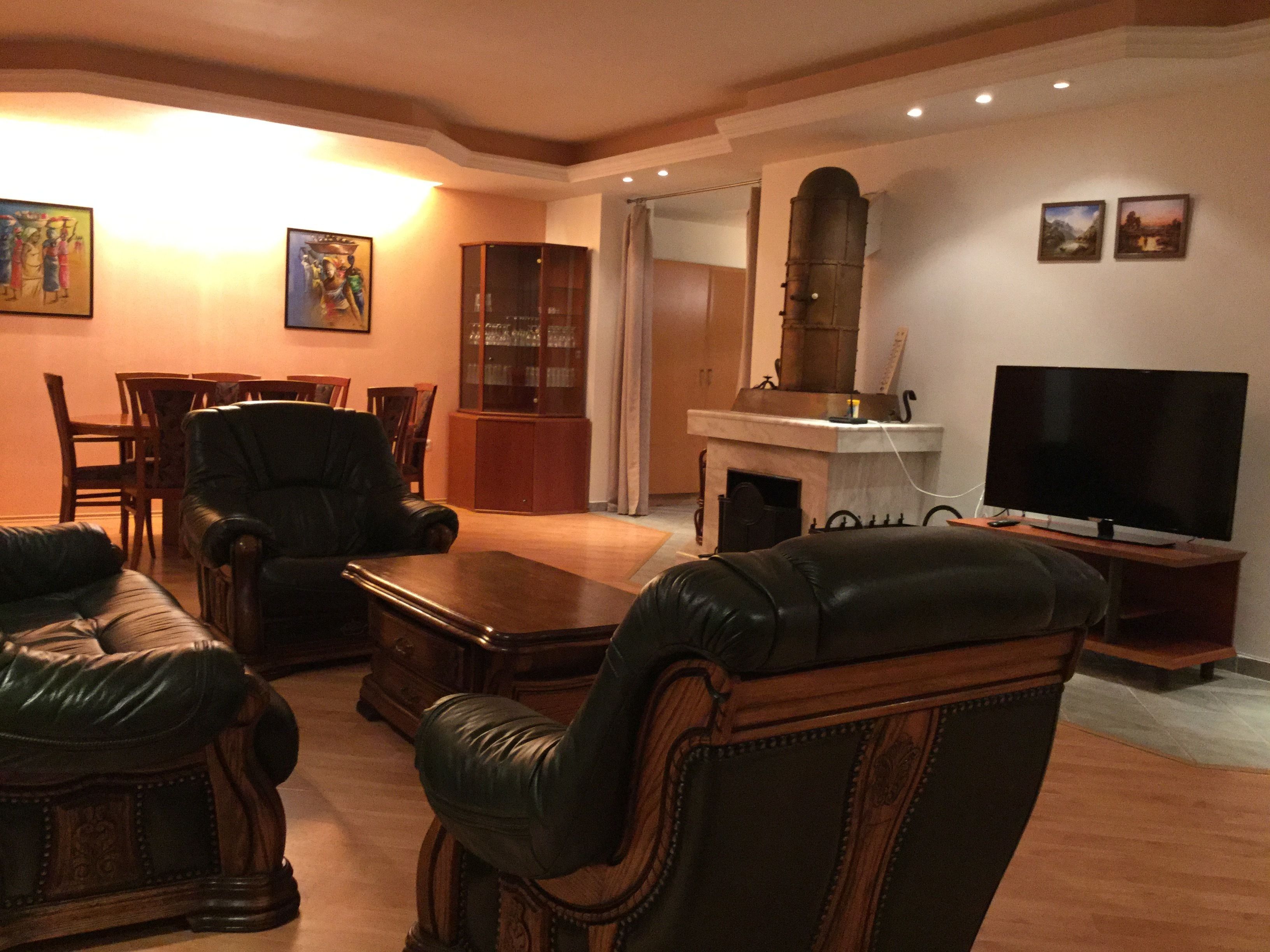 A living room with leather sofas, a wooden coffee table, a fireplace, a television, and framed pictures on the wall.