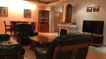 A living room with leather sofas, a wooden coffee table, a fireplace, a television, and framed pictures on the wall.
