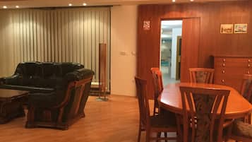 Un comedor con una mesa y sillas de madera, un sofá de cuero negro y una lámpara de pie alta.