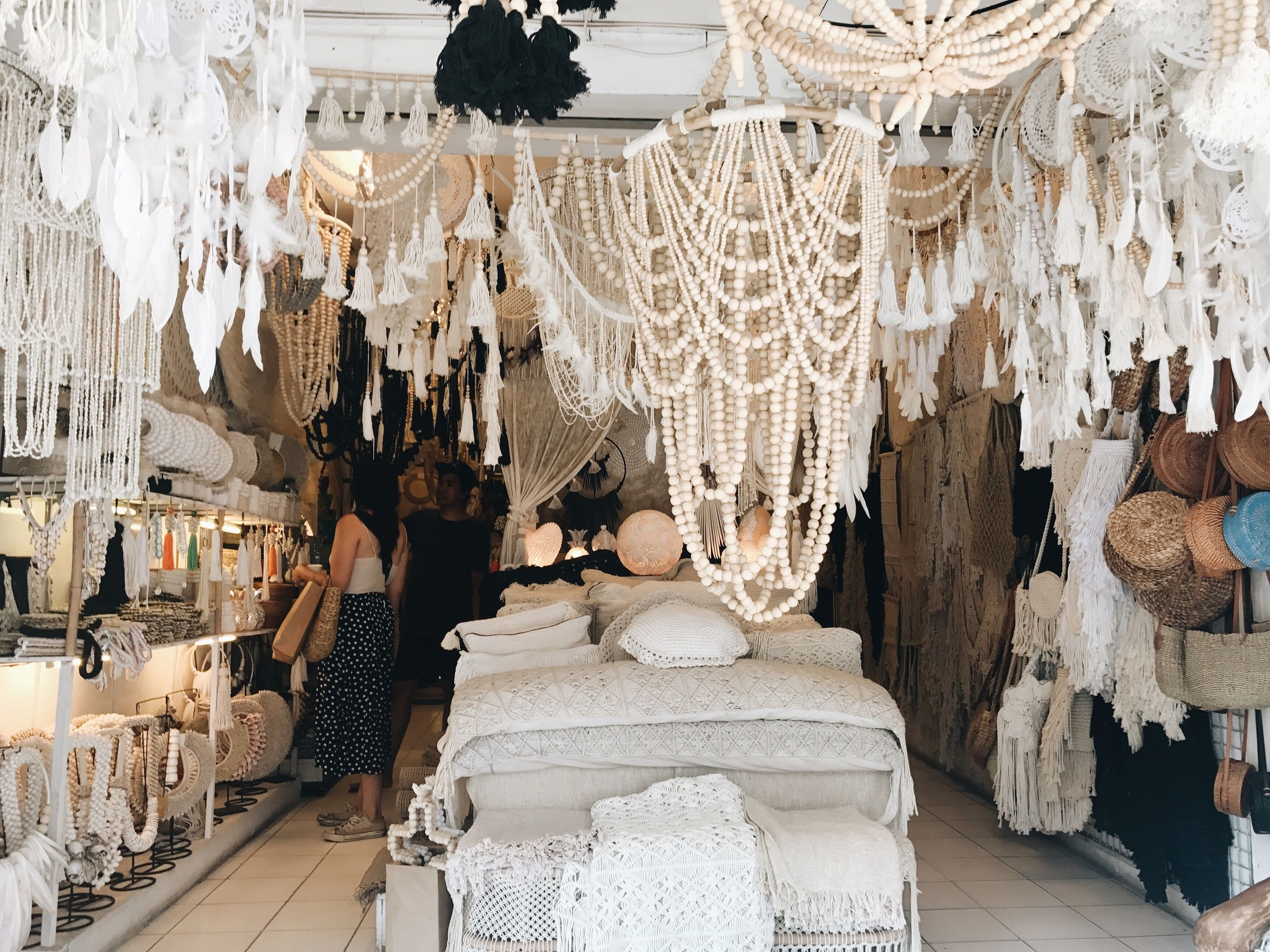 A boutique hotel interior with a central bed area, surrounded by various handmade decor items like macramé and beaded accessories.