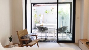 A modern bedroom with a large sliding glass door leading to a balcony with a white sink and two chairs. - Lloyd's Inn Bali (Seminyak)