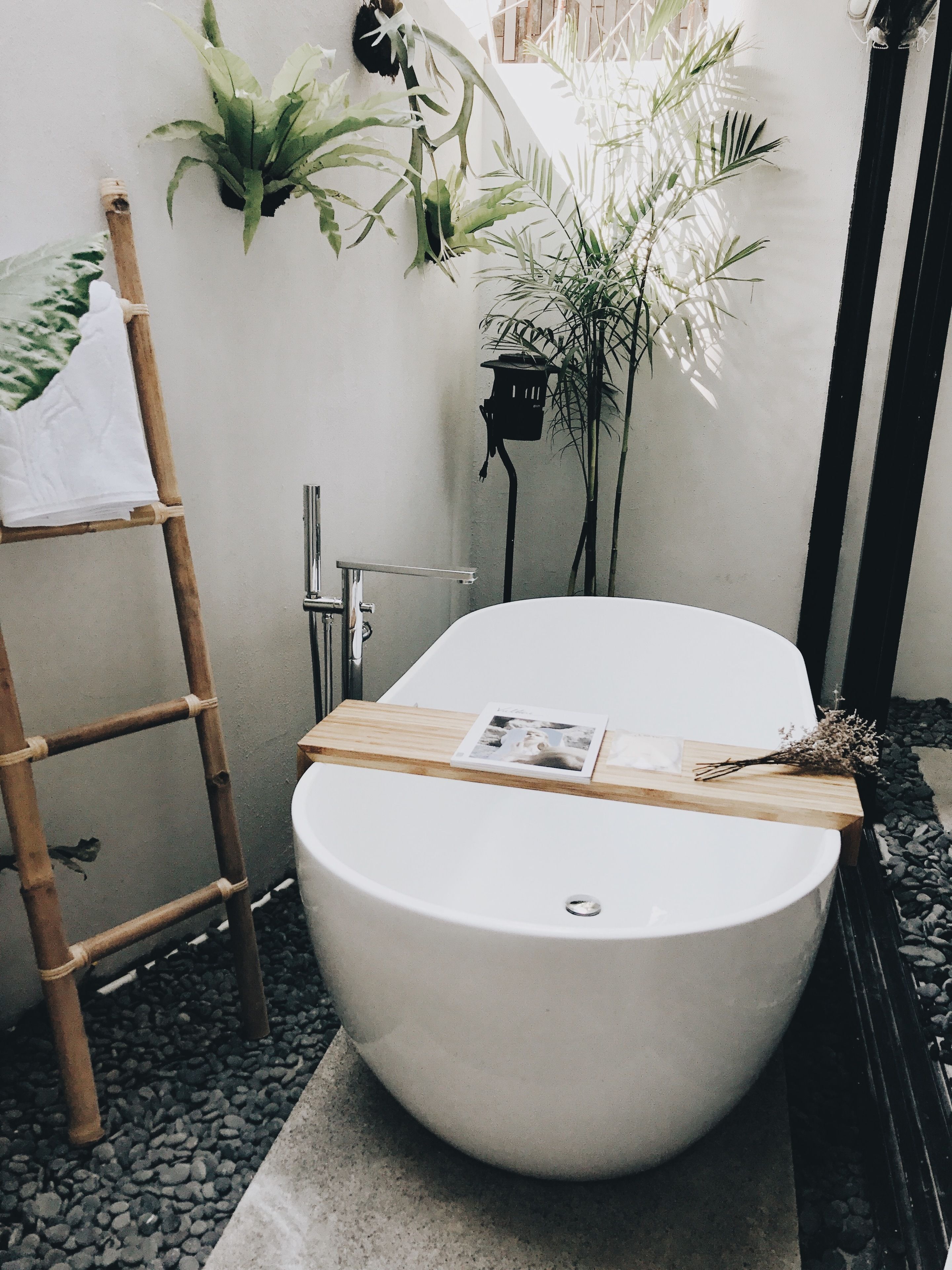 A modern bathroom with a freestanding bathtub, a wooden shelf, and a ladder.