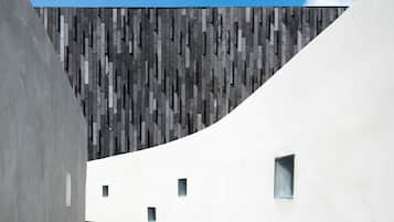 A modern architectural structure with a curved white wall and a patterned wall in the background.