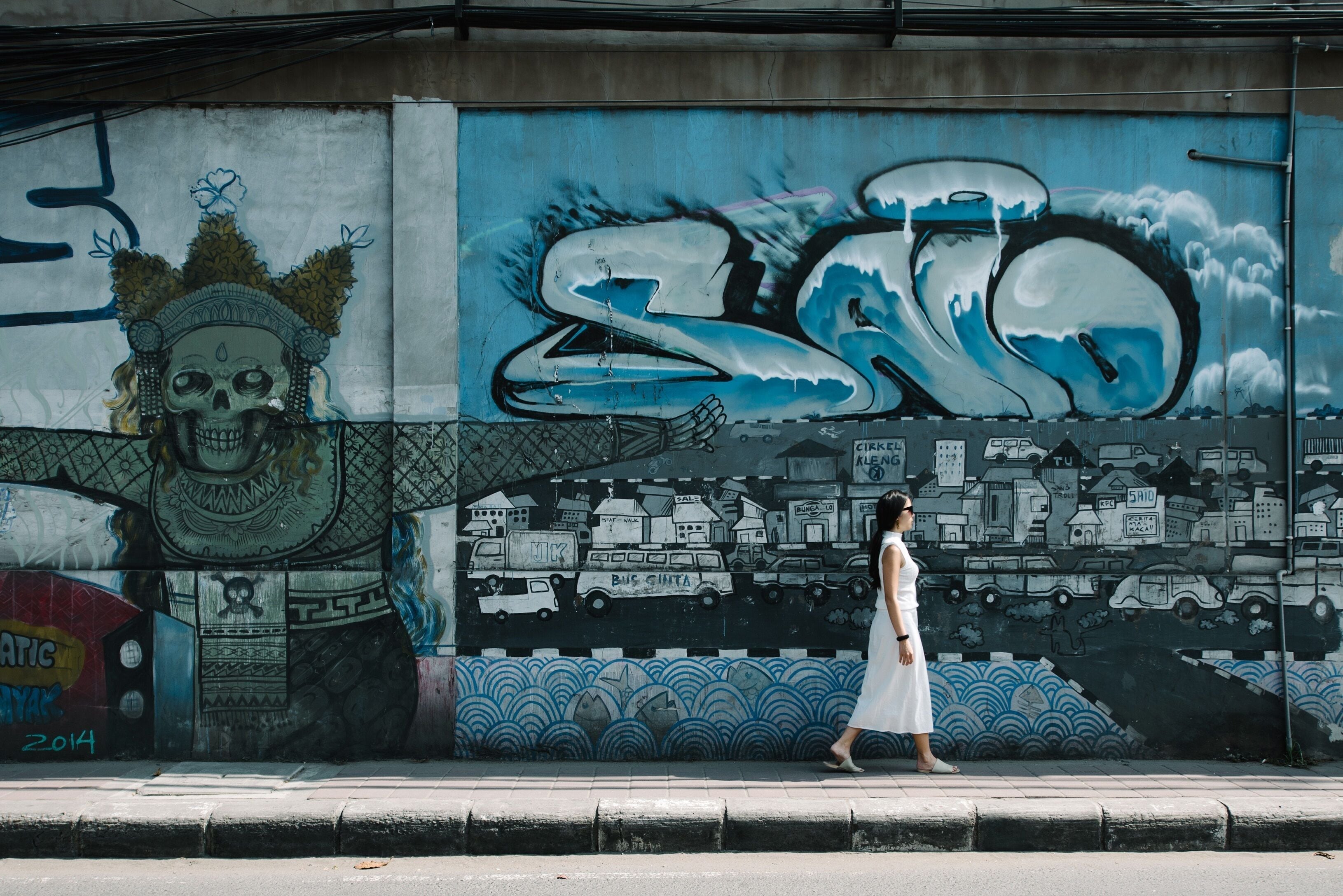 A mural with a skull, a bus, and a cityscape.