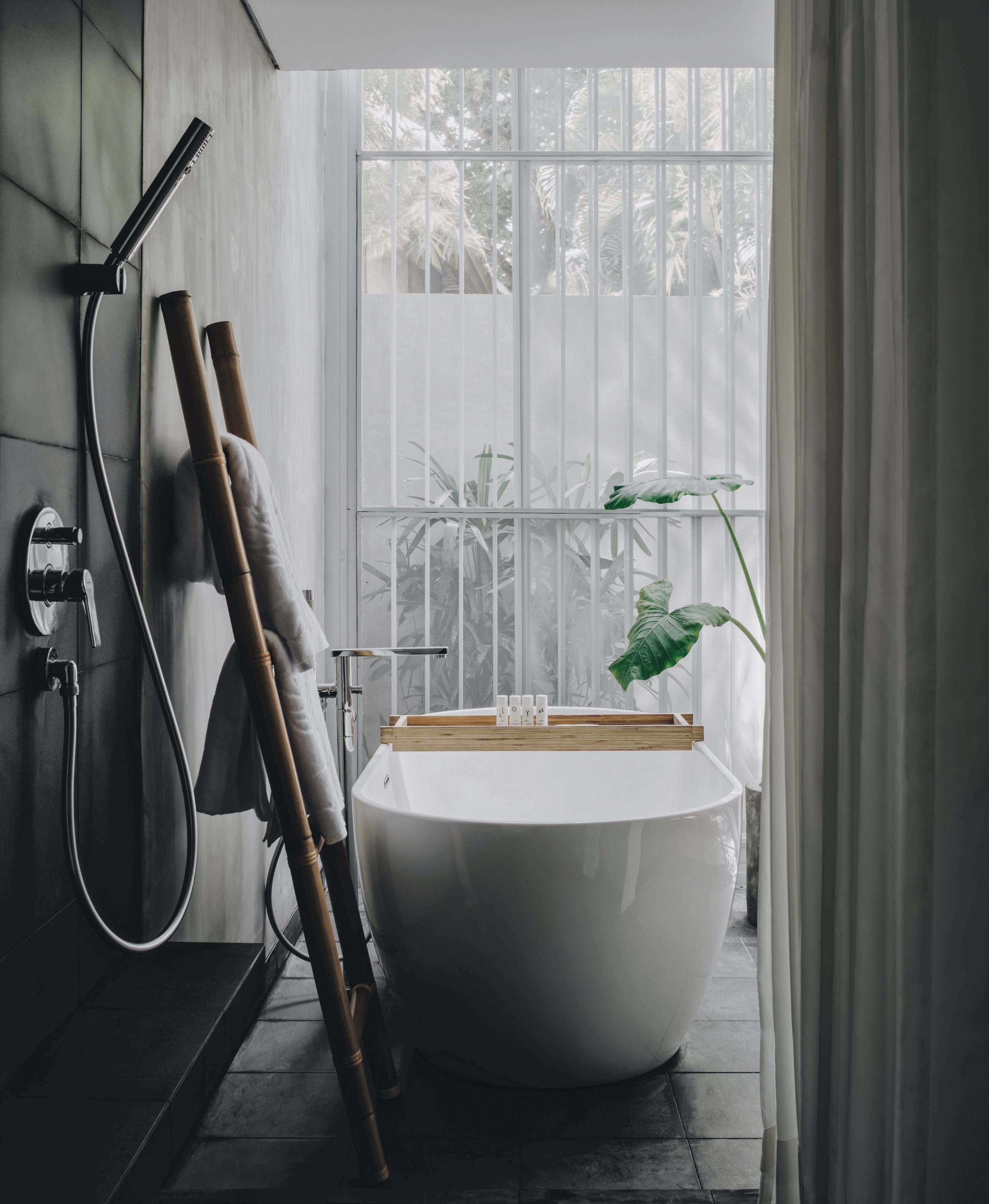 Une salle de bain moderne avec une baignoire sur pieds, une douche et une grande fenêtre donnant sur un paysage verdoyant.