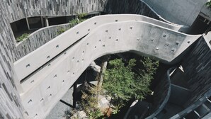 A modern architectural structure with curved balconies and a central garden area. - Lloyd's Inn Bali (Seminyak)