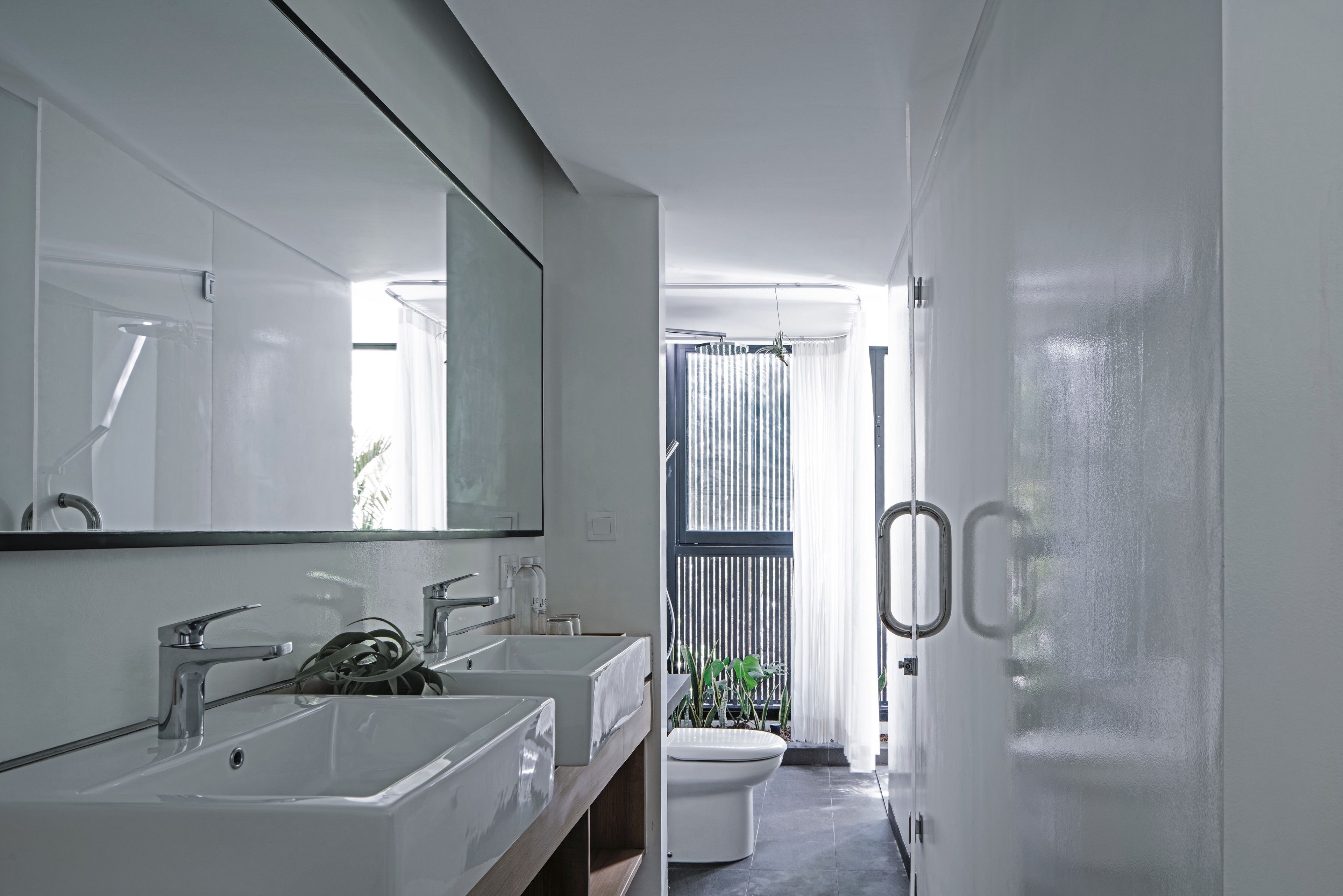 Un baño moderno con dos lavamanos, un espejo grande y un inodoro.