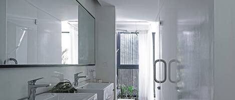 Un baño moderno con dos lavamanos, un espejo grande y un inodoro.