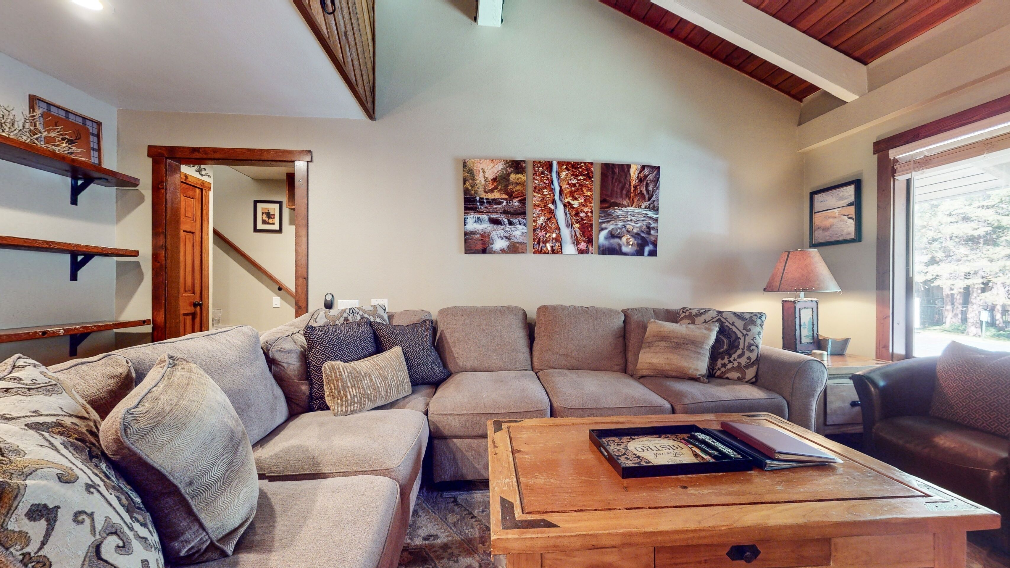 Un salon avec un canapé d’angle, une table basse et un tableau accroché au mur.