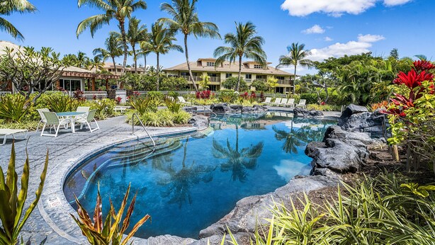 A resort pool with tropical landscaping, a covered seating area, and a building with balconies. - Waikoloa Beach S C3 2 Bedroom Villa by RedAwning (Waikoloa)