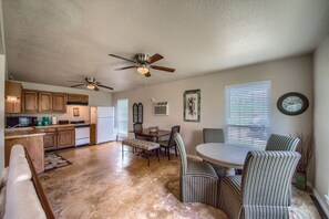 A spacious kitchen with wooden cabinets, a dining area with striped chairs, and ceiling fans. - Tranquility By The Shore Cl1105b 4 Bedroom Home by RedAwning (Canyon Lake)
