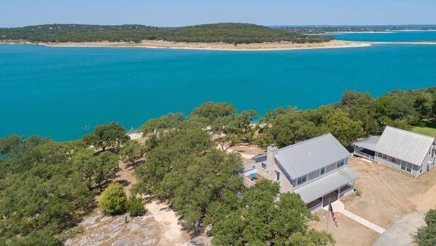 A coastal property with two main buildings, a sandy beach, and a clear view of the sea.