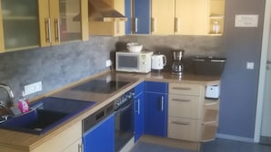 Una cocina con armarios azules y de madera, un microondas, un hervidor y una cafetera.