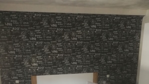 Un dormitorio con cama, cabecera de madera, ropa de cama blanca y una pared decorada con diversas frases sobre el amor.