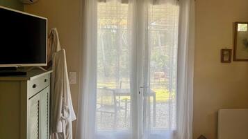 Una stanza con televisore, mobile, finestra con tende, un tavolino e termosifone.