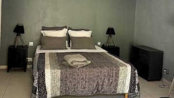 A bedroom with a bed, two bedside tables, a ceiling fan, and a nightstand with a lamp.
