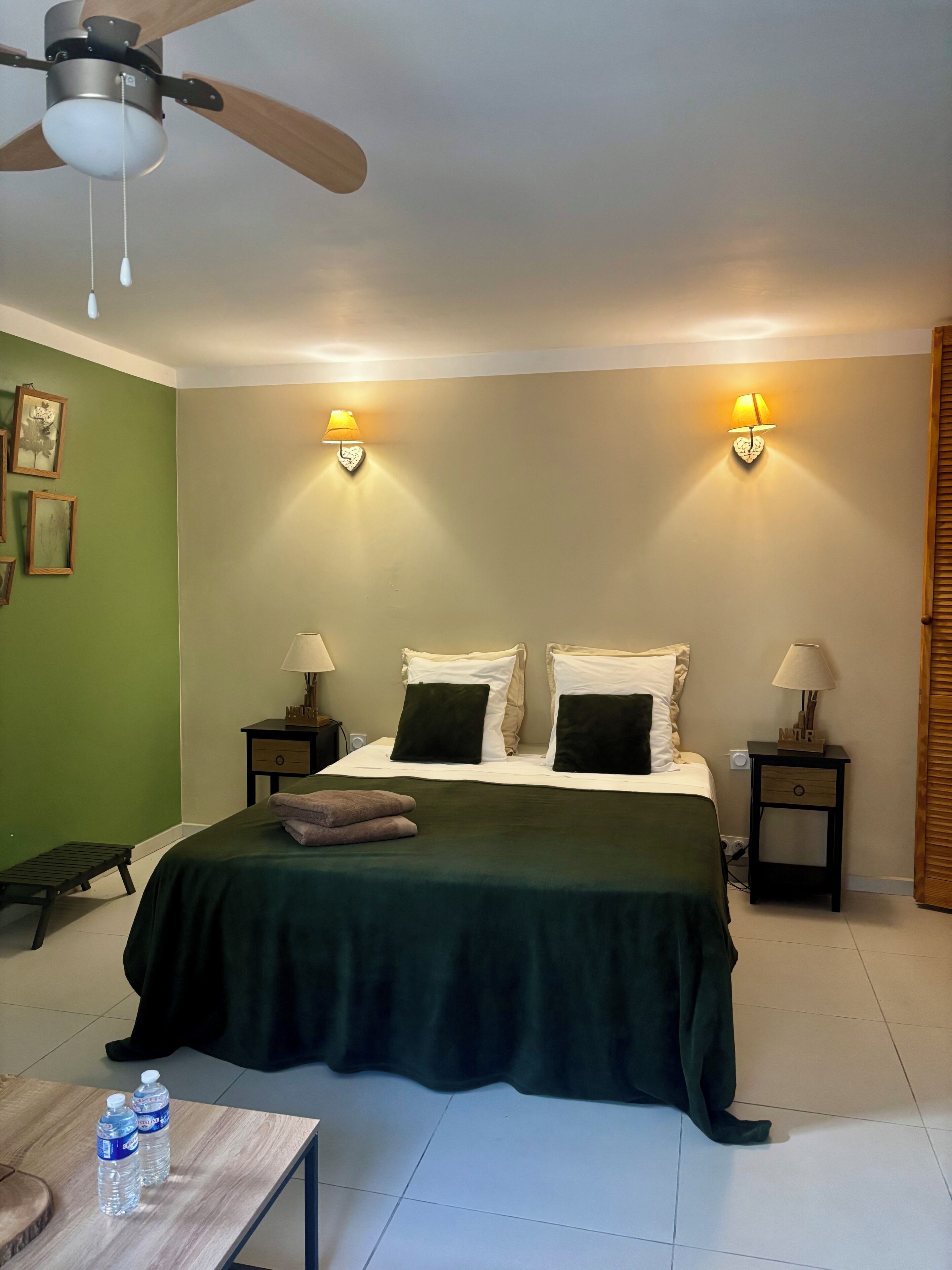 A bedroom with a bed, two bedside tables with lamps, a ceiling fan, and a nightstand with a lamp.