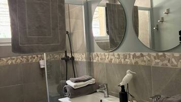 Une salle de bain avec une douche à parois de verre, un lavabo avec un miroir et un porte-serviettes.
