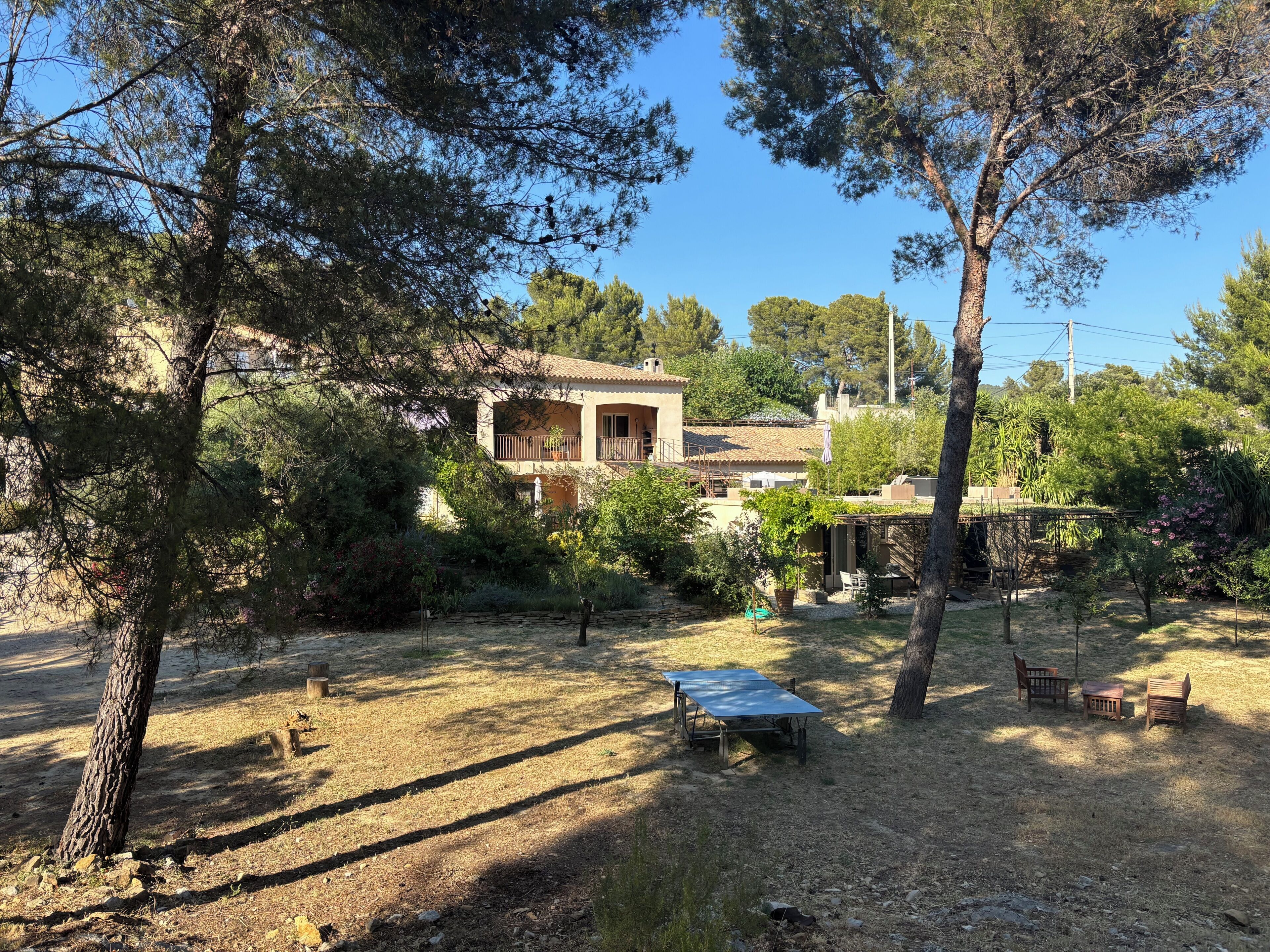 Une maison de campagne rustique, dotée d’un balcon, entourée d’arbres et bordée d’une pelouse.
