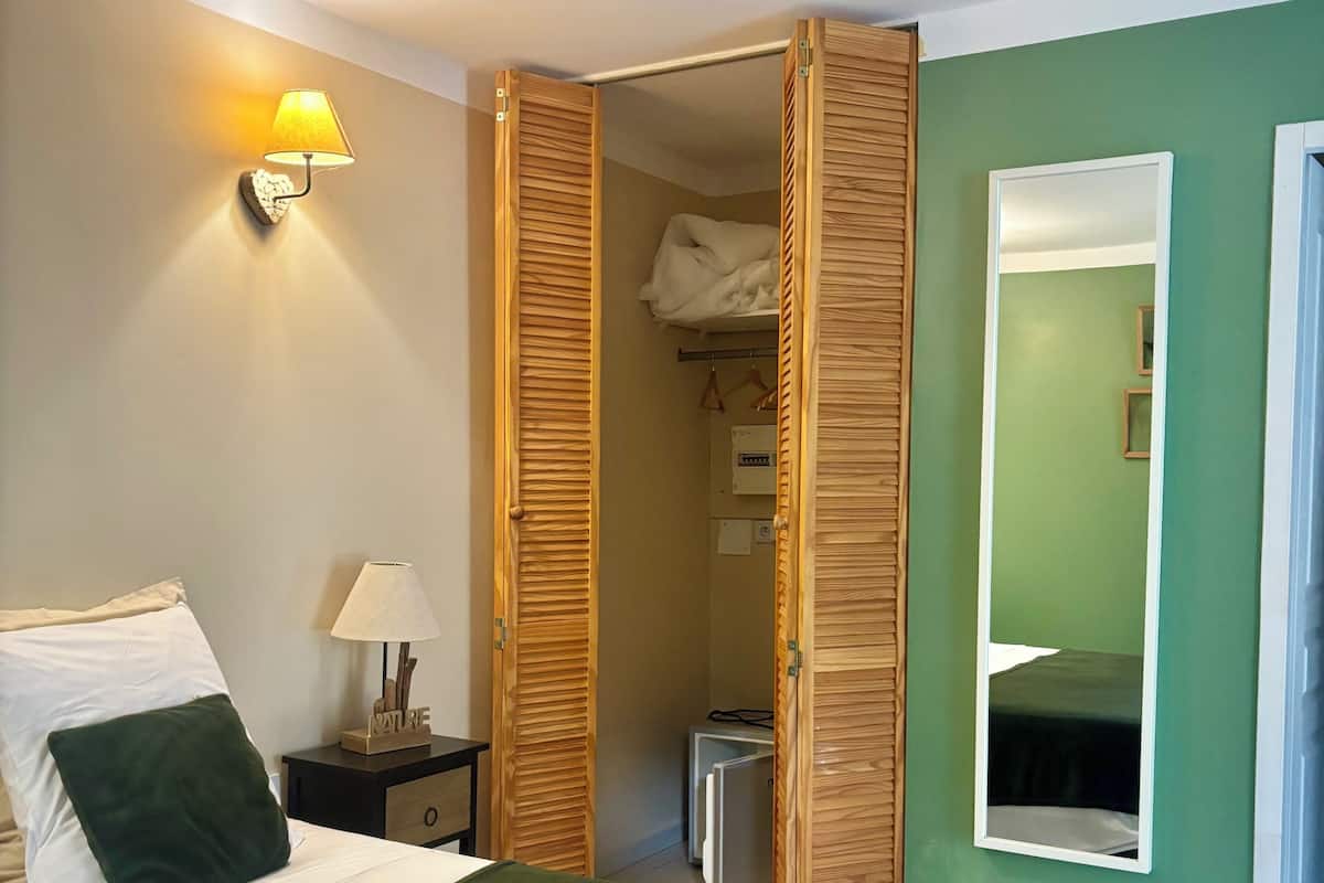 Une chambre d’hôtel comprenant un lit, une table de chevet, une lampe, un miroir et une armoire.