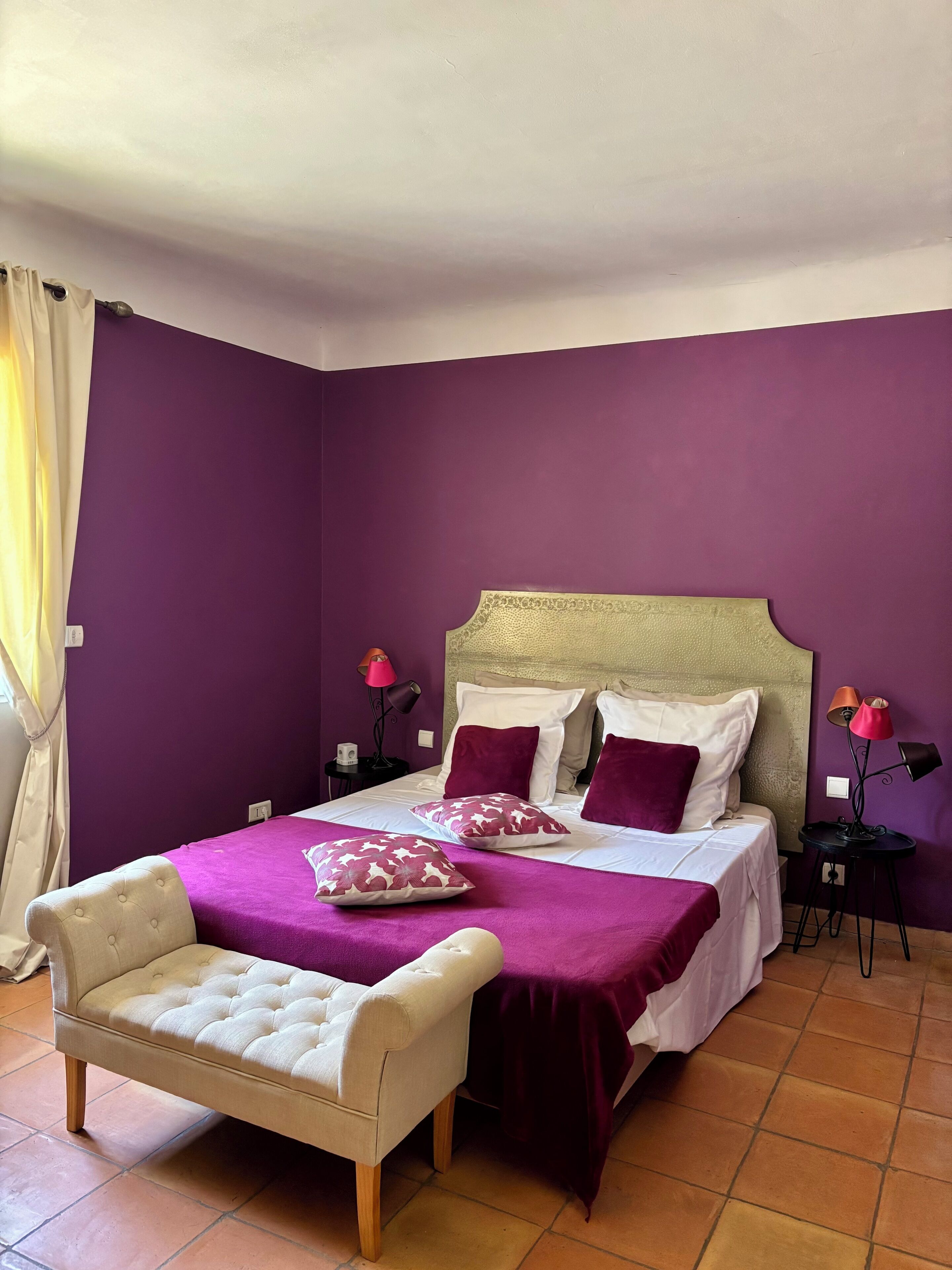 Un dormitorio con una cama, una silla y dos mesitas de noche con lámparas.