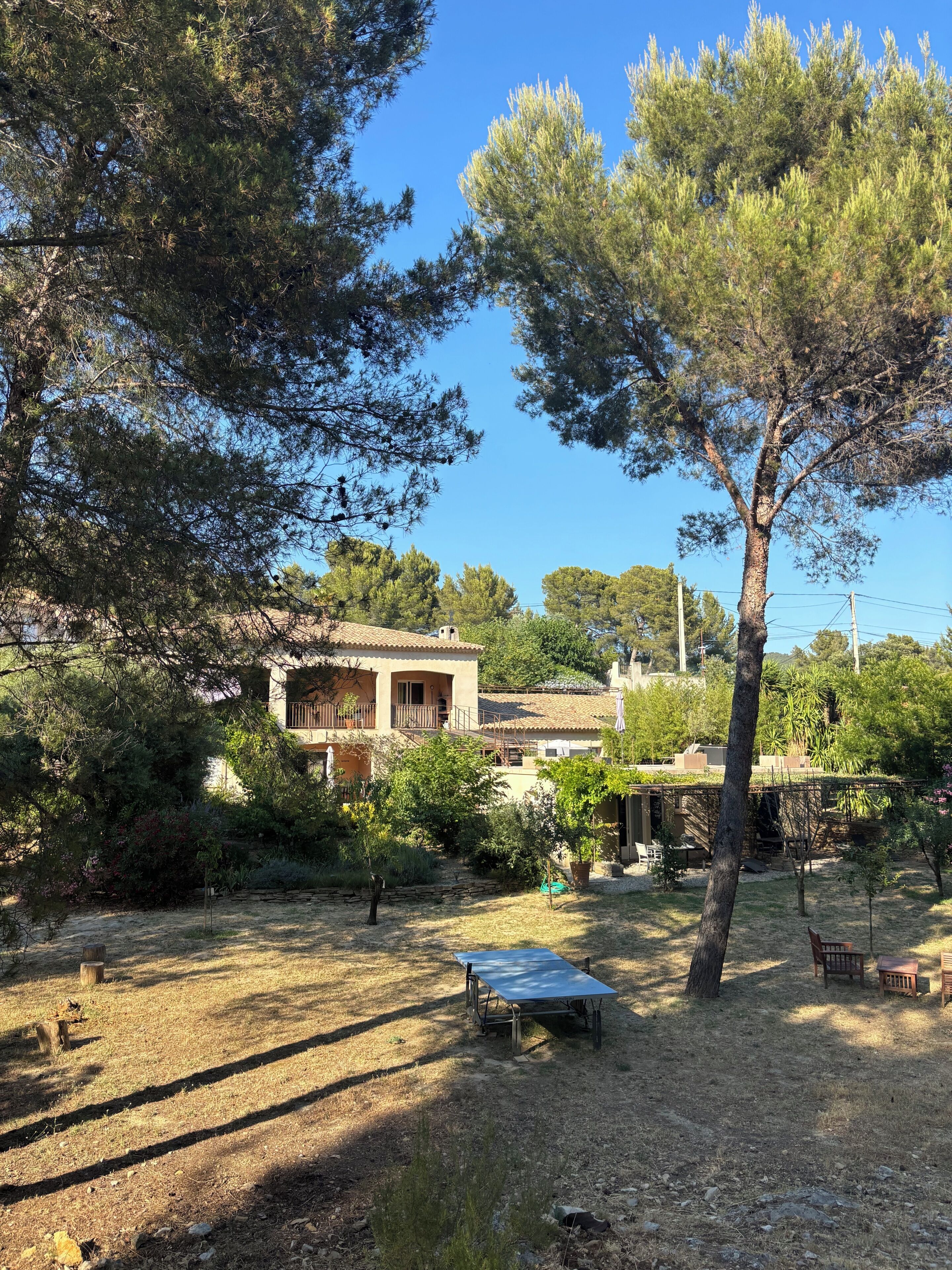Una casa con balcón, rodeada de árboles y un jardín.