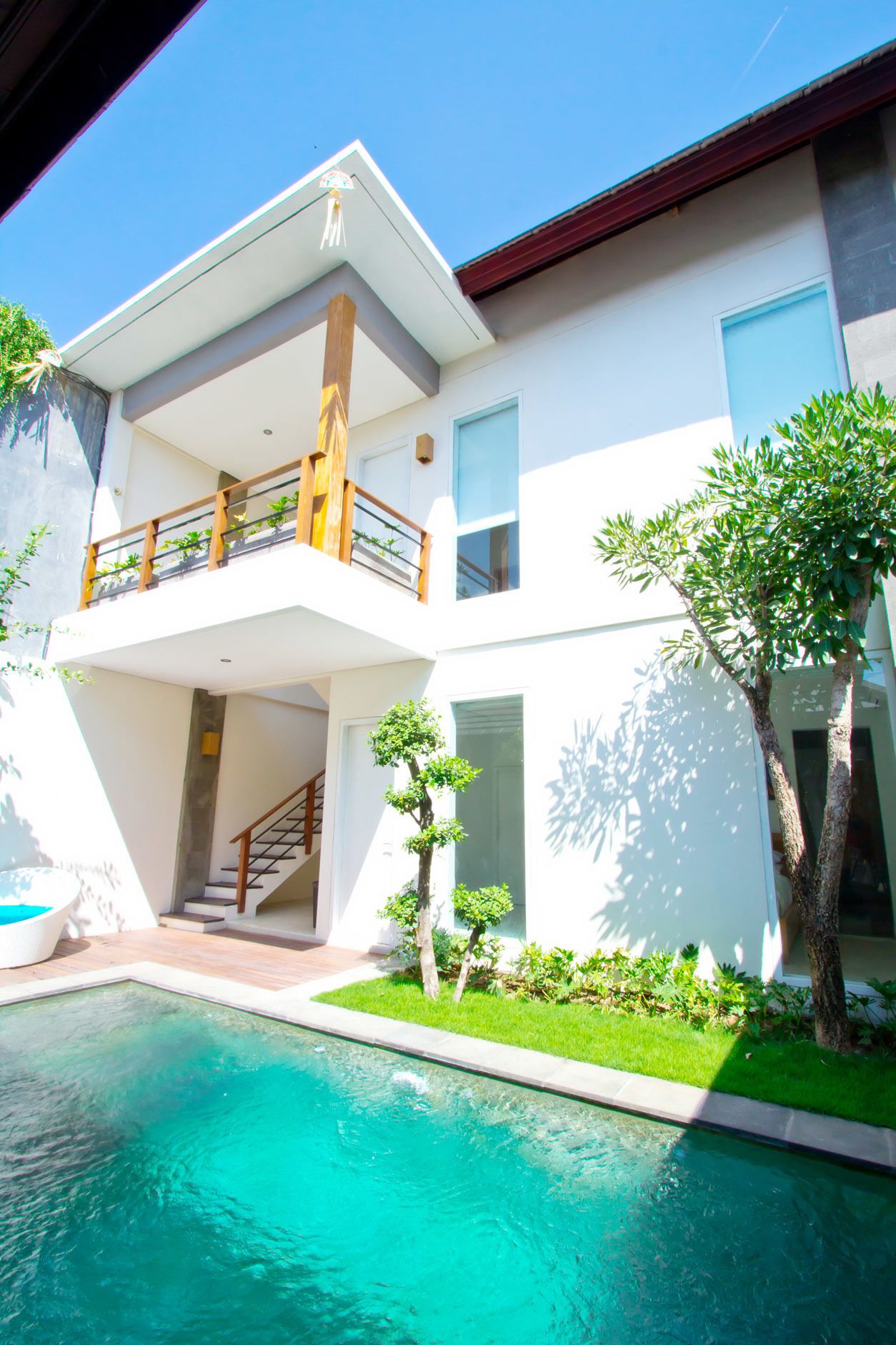 Una moderna casa a due piani con piscina, un balcone e un giardino curato.