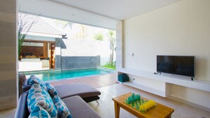 A modern living room with a pool, a sofa with patterned cushions, a flat-screen TV, and a chessboard. - Apple Villa and Apartment (Kerobokan)
