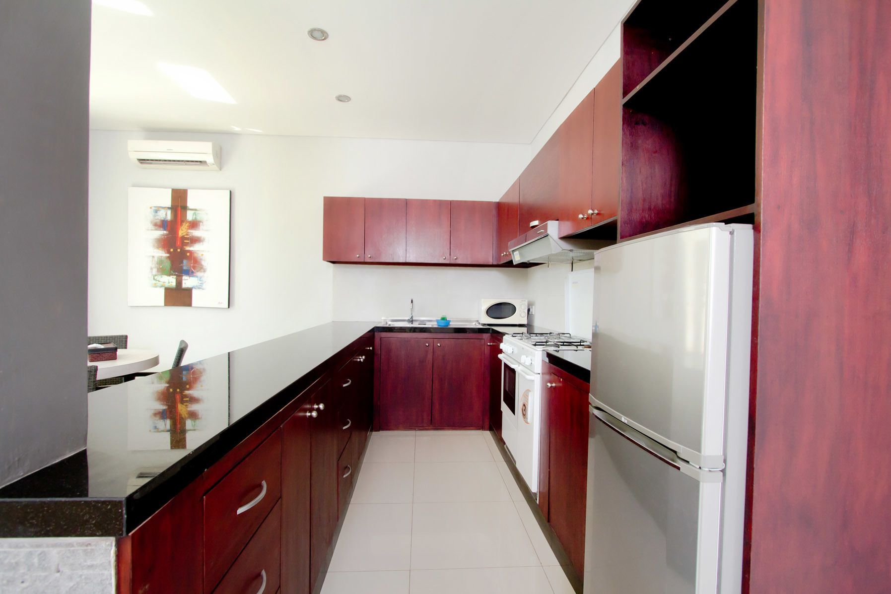 Une cuisine moderne avec des meubles de couleur bois foncé, un réfrigérateur blanc et une cuisinière.