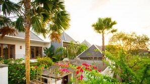 A residential area with houses, palm trees, and flowering plants. - Apple Villa and Apartment (Kerobokan)