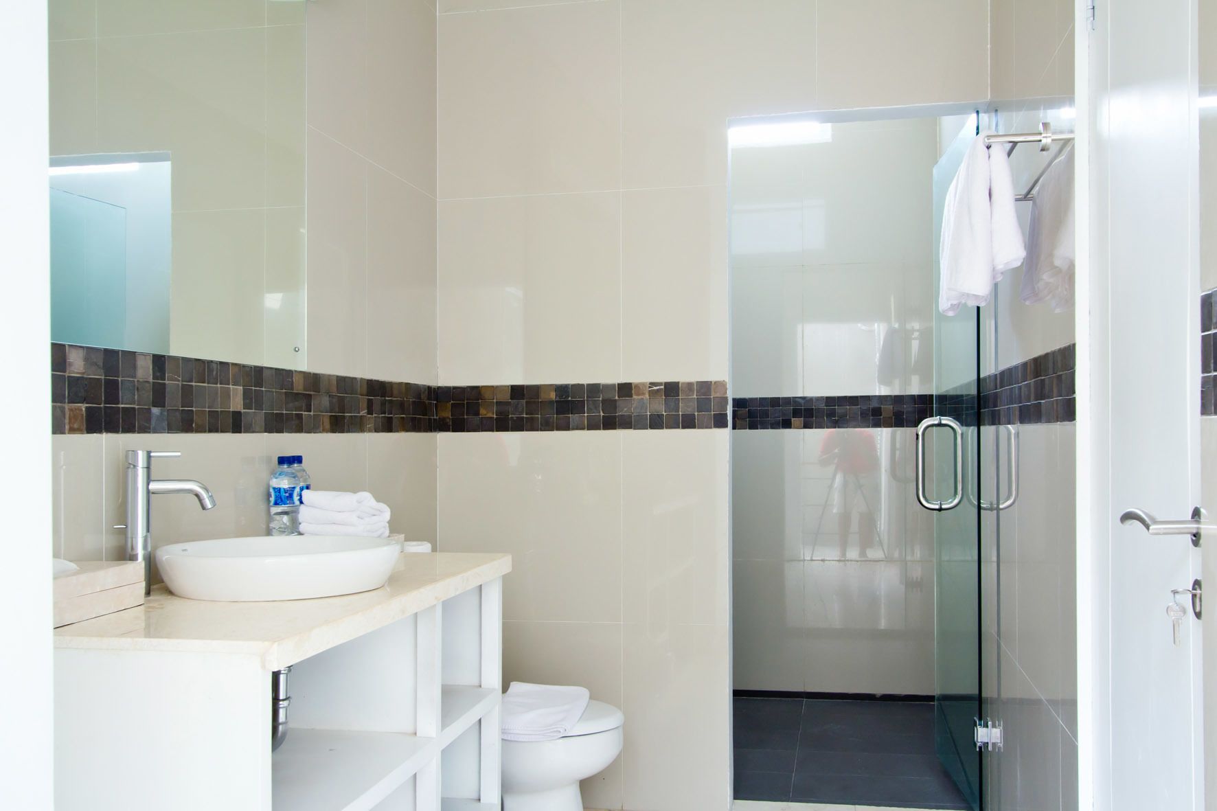 A modern bathroom with a large mirror, a sink, and a shower area.