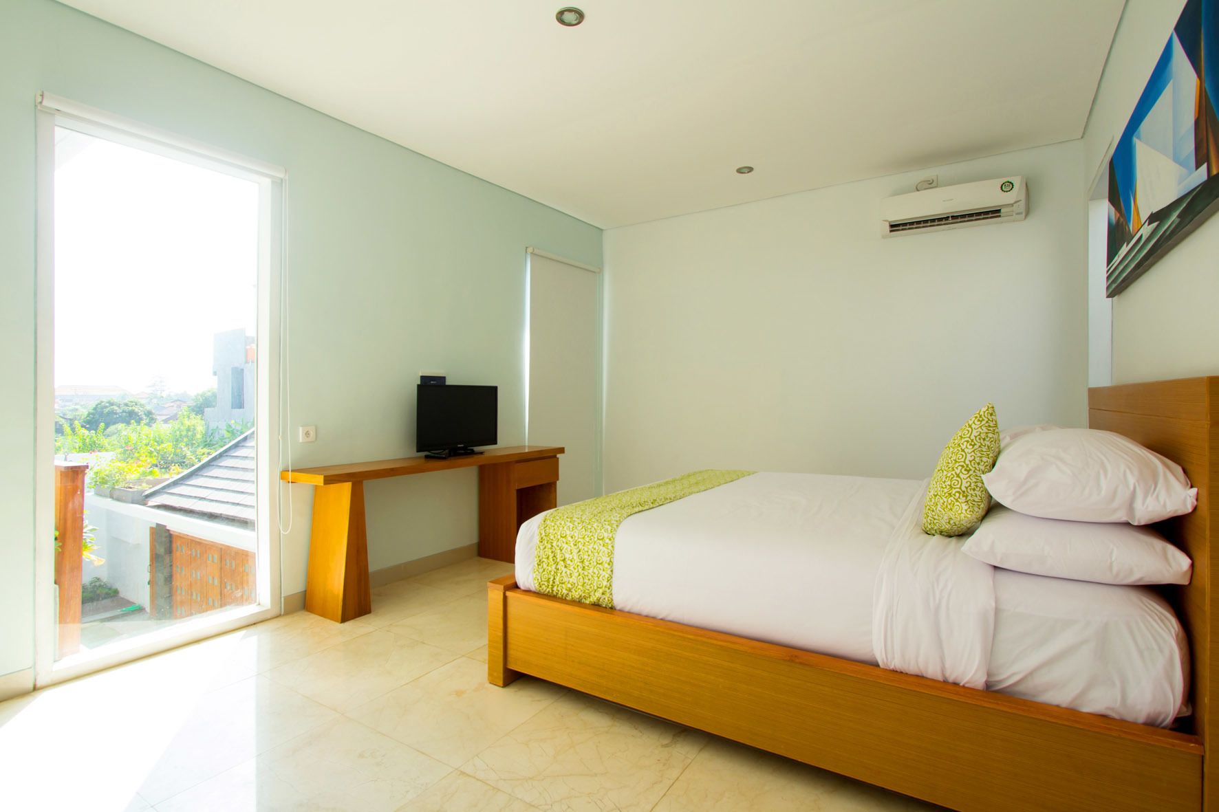 A bedroom with a bed, a desk, and a television.