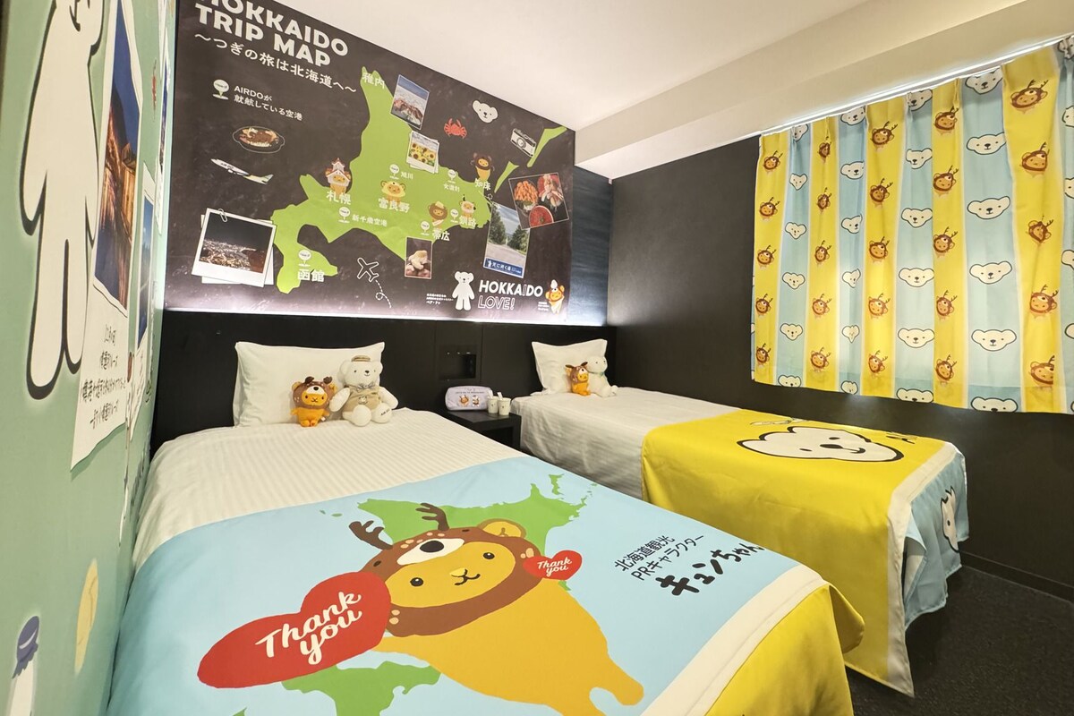 A hotel room with two beds, a map on the wall, and a curtain with animal patterns.