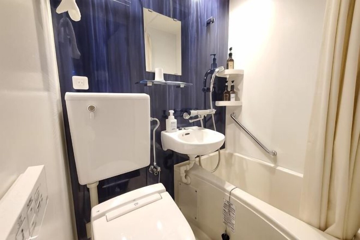 A bathroom with a toilet, sink, mirror, and shower.