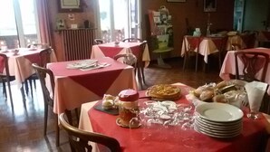 En restaurang med bord täckta av röda dukar, trästolar och ett urval av rätter och glas på borden.