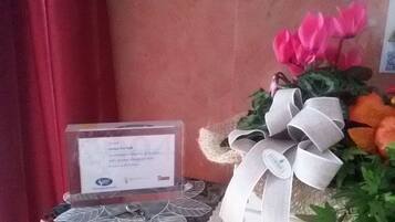 Un diploma en marco sobre un atril con un lazo, junto a un ramo de flores con un gran moño.