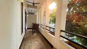 A corridor with a ceiling fan, a chair, and a railing with a view of greenery outside. - WORLD WALKERs - Hostel (Siem Reap)
