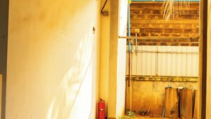 A hallway with tiled flooring, a red fire extinguisher, and a wooden fence in the background. - WORLD WALKERs - Hostel (Siem Reap)