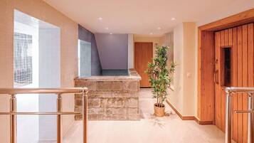 A modern interior with a stone bench, a potted plant, and wooden doors.