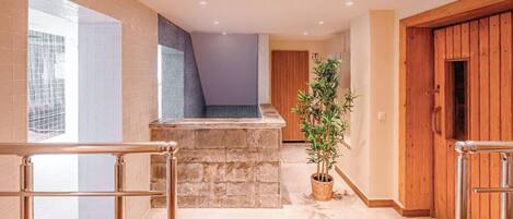 Un interior moderno con un banco de piedra, una planta en maceta y puertas de madera.