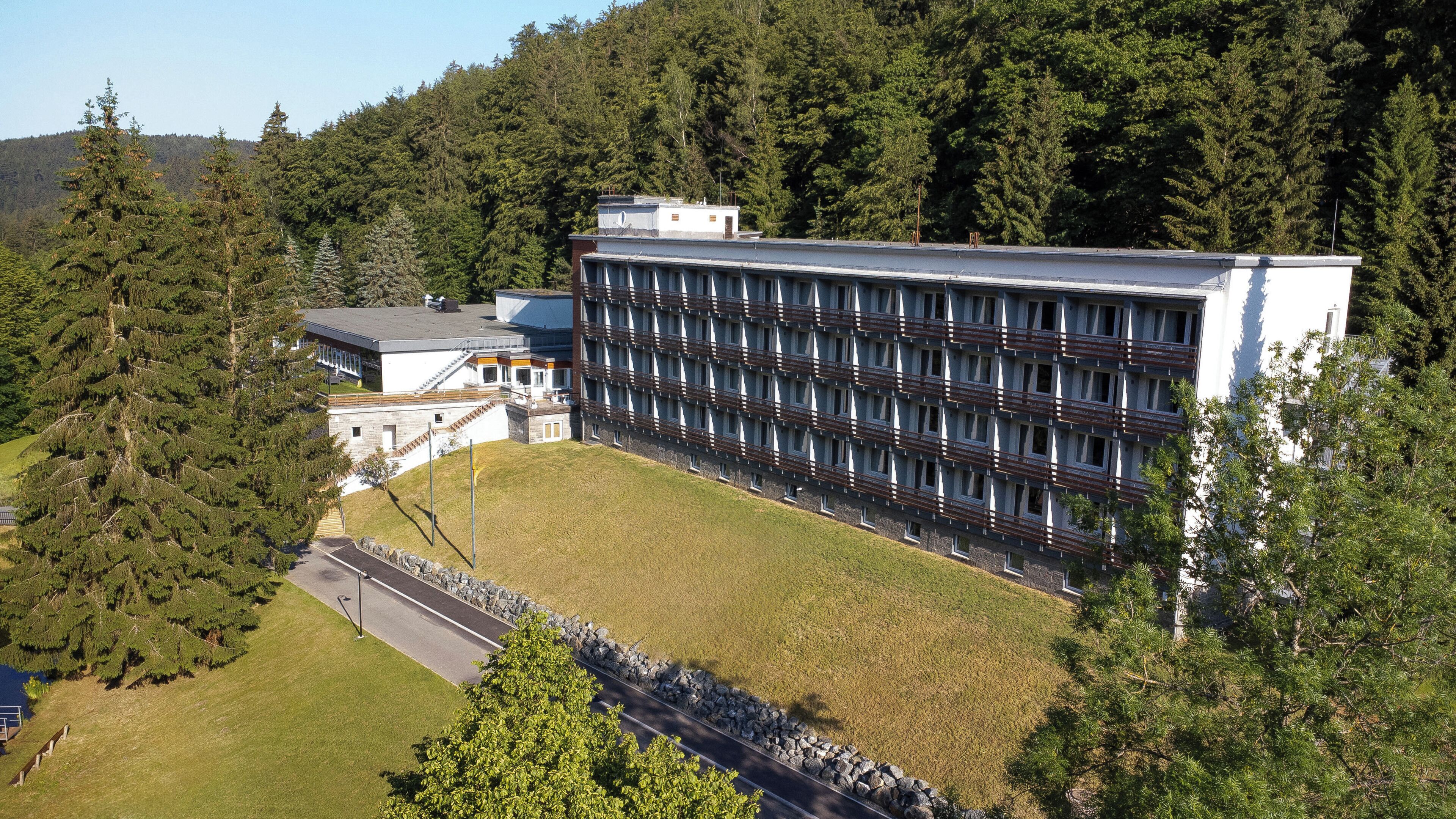 A modern building with a symmetrical facade, a central courtyard, and a surrounding forested area.