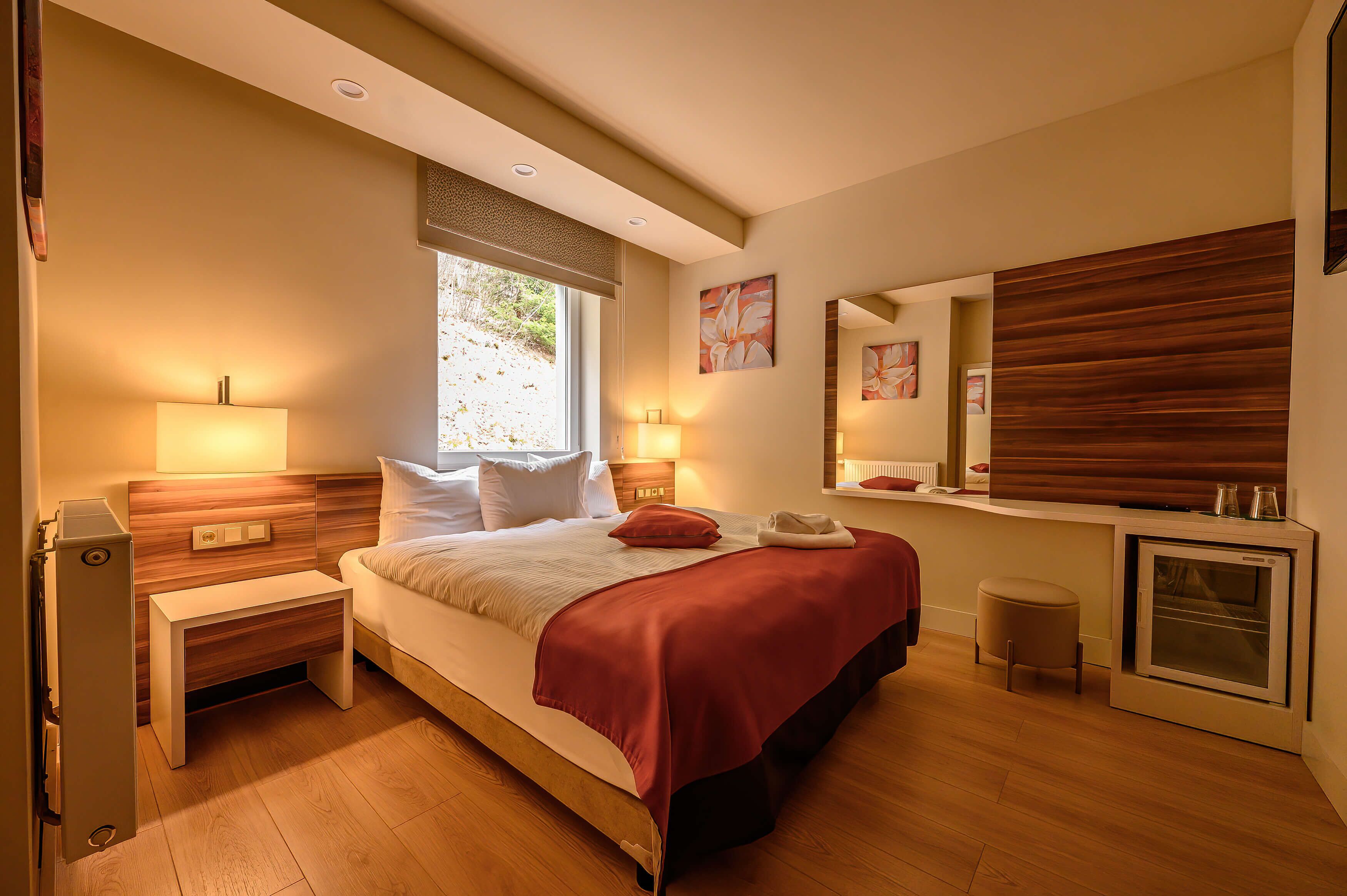 Un dormitorio moderno con cama, mesitas de noche, un espejo y un horno empotrado.