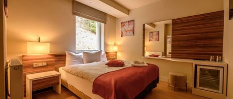 Un dormitorio moderno con cama, mesitas de noche, un espejo y un horno empotrado.