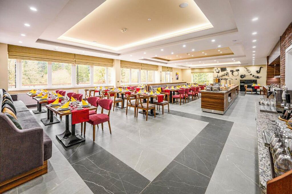 A spacious restaurant with multiple dining areas, red chairs, and a central bar area.