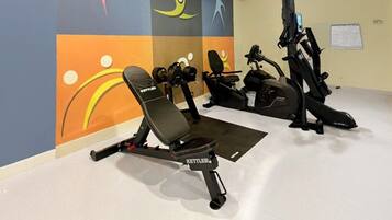 A gym with a Kettler chair and elliptical machine.