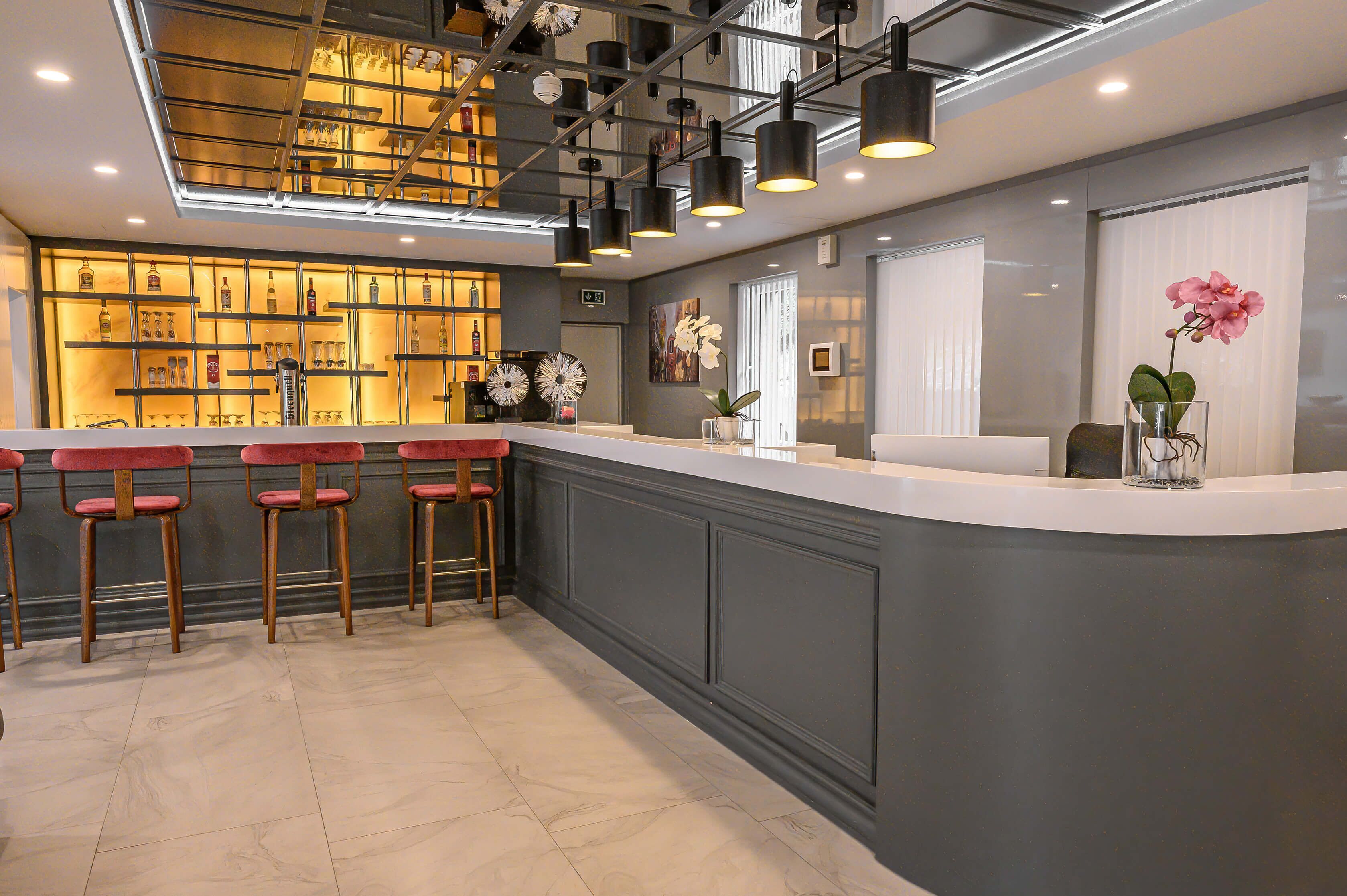 A bar area with a counter, stools, and a display of bottles.