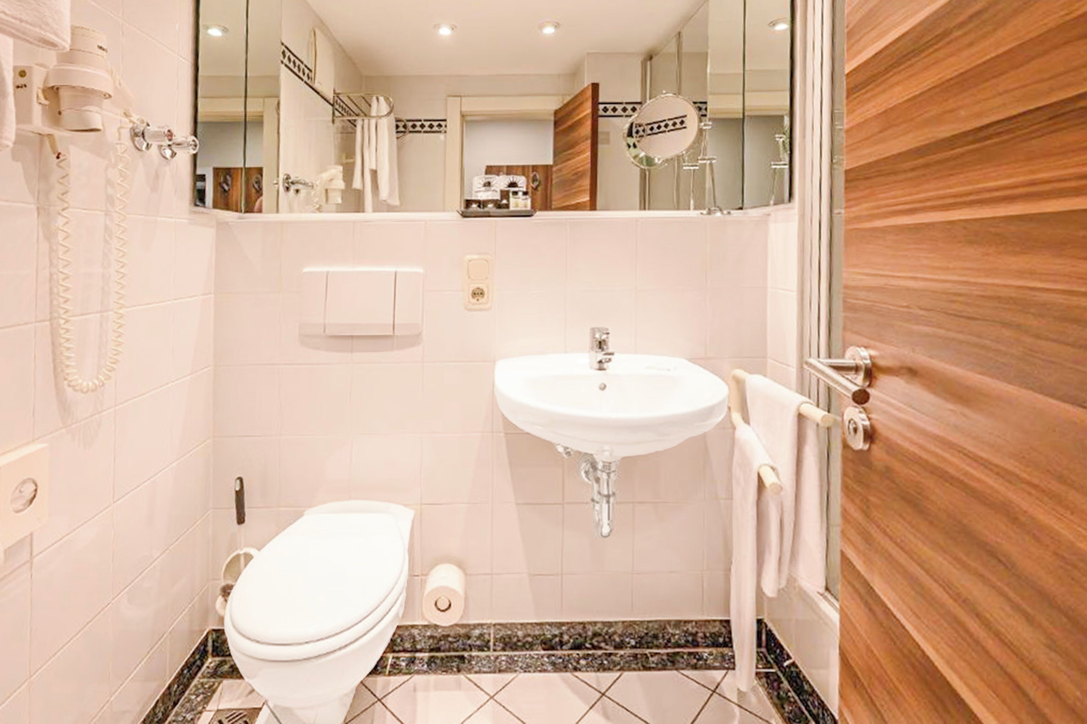 A bathroom with a toilet, sink, and mirror.