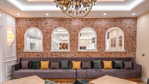 A modern living room with a brick wall, a sofa, and a chandelier. - Sunday Schwarzbachtal Hideaway Resort (Markneukirchen)
