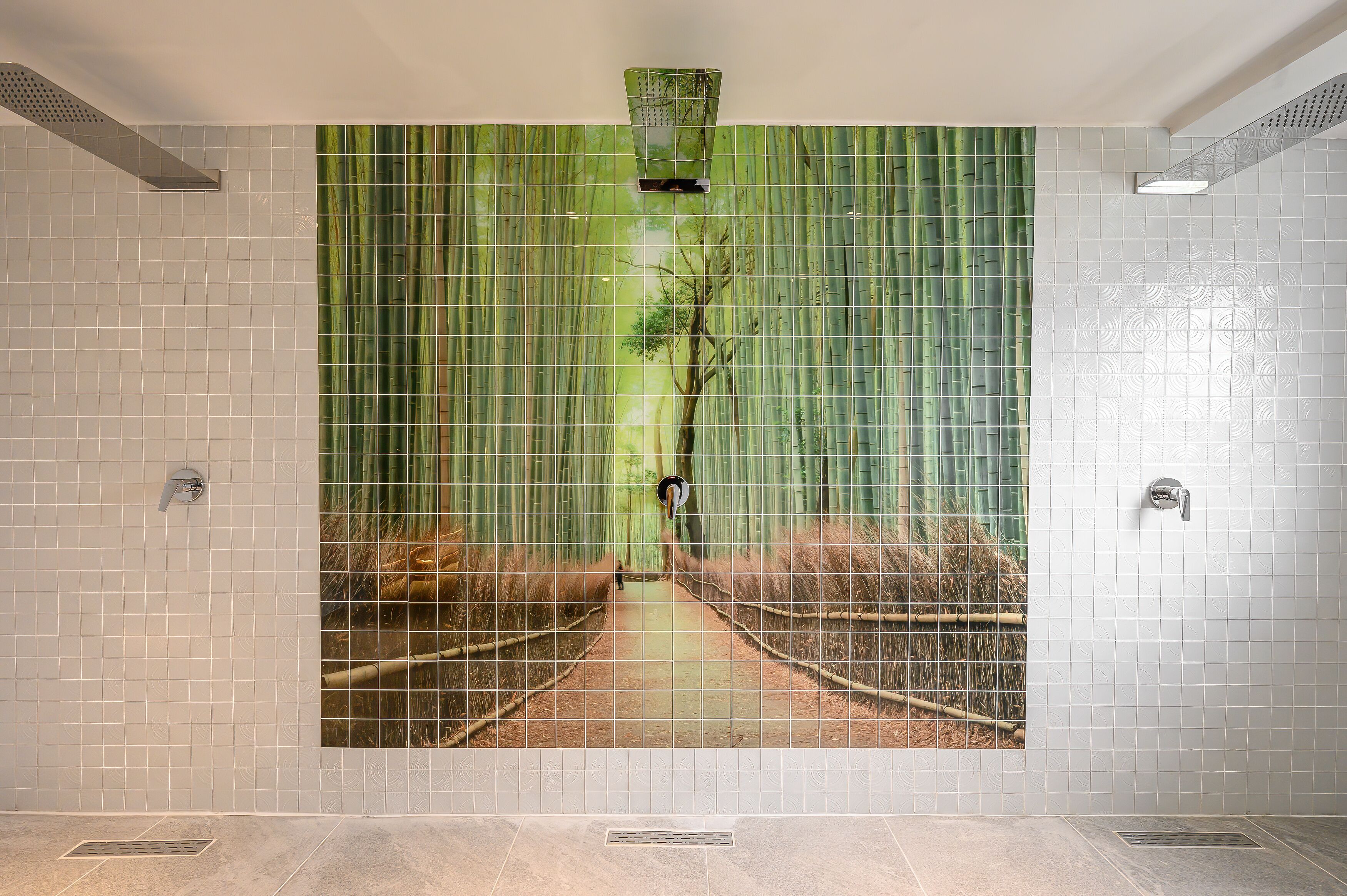 A bathroom with a large mural of a forest path, tiled walls, and a shower area.